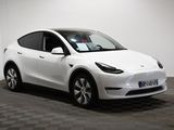 a white tesla model y parked in a room with a checkered floor