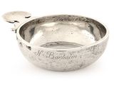 a silver bowl with a spoon in it on a white surface