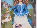 La poupée qui se trouve dans la boîte porte une robe bleue et une jupe blanche.