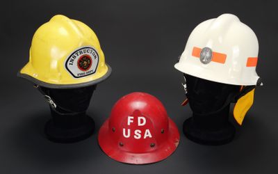 trois casques de pompiers sont alignés sur une surface noire