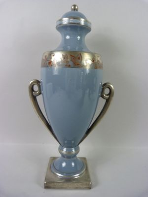 un vase bleu à bord doré posé sur un socle