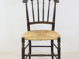 an image of a wooden chair with a wicker seat on a white floor