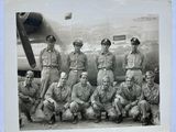 black and white photo of a group of men in uniform posing in front of an airplane