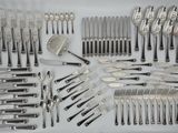 a lot of silverware on a table with spoons and knives