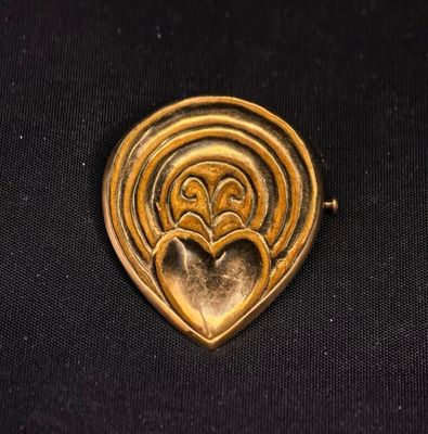 a close up of a gold heart shaped broocher on a black background