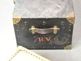 a black suitcase with a gold handle next to a white box