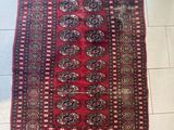 a red and black rug on a white tiled floor