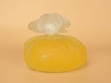 un savon jaune surmonté d'une fleur, posé sur une surface jaune