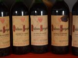 six bottles of red wine are lined up on a table