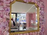 un miroir avec un cadre doré orné de fleurs roses