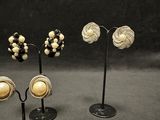 three pairs of earrings are displayed on a black stand