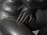 statue of a woman sitting on a rock with her hands on her knees
