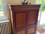 a cabinet in the corner of a room with a painting on the wall