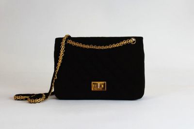 un sac à main noir muni d'une chaîne dorée sur fond blanc