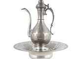 une théière ancienne en argent posée sur une soucoupe, avec une autre soucoupe en dessous