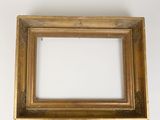 an old gold picture frame with a white background and a black object