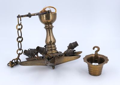 an antique brass oil lamp with a chain around it and a cup on the ground