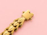 an image of a gold bracelet with a lock on a pink background