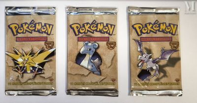 three packs of pokemon trading cards on a white surface