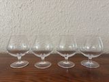 four empty wine glasses lined up on a table in front of a wall