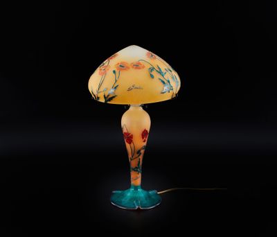 une lampe de table en verre surmontée d'un abat-jour jaune