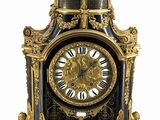 une horloge noire et dorée surmontée d'un ange