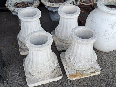 quatre vases blancs posés les uns à côté des autres par terre