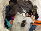 a pile of clothes in a bag with a pair of shoes