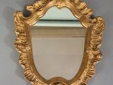 un miroir doré accroché au mur au-dessus d'un lavabo