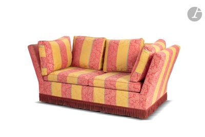 un canapé rayé rouge et jaune, avec des coussins dessus