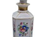 a small white bottle with a floral design on it