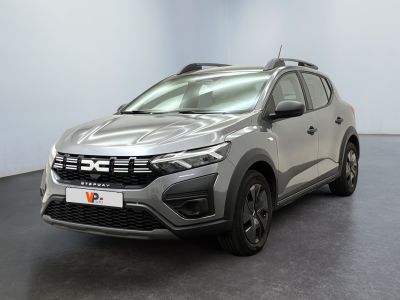 Une voiture argentée est garée dans une pièce au sol noir.