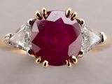 a close up of a ring with a red stone surrounded by white diamonds