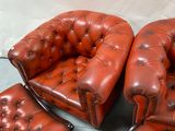 four brown leather chairs and a foot stool in a room