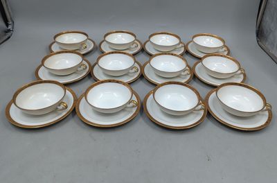 une pile de tasses et soucoupes en porcelaine blanche et dorée