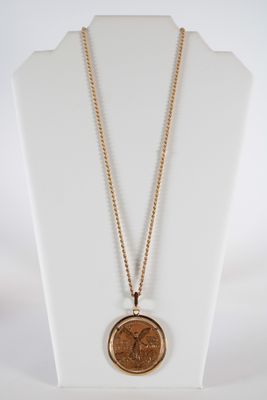 a gold necklace with a coin on a white mannequin