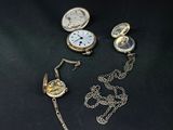 three different types of pocket watches on a black surface