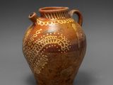 un vieux vase marron orné de motifs sur un fond gris
