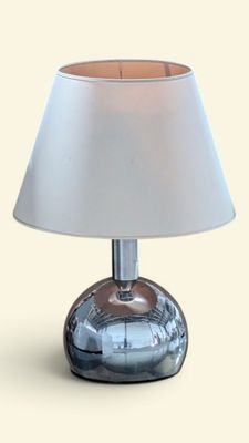 une lampe de table argentée avec un abat-jour blanc