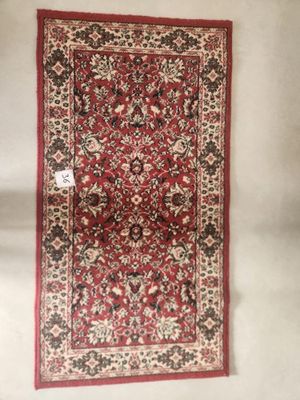 a red rug hanging on a wall next to a white wall