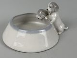 a dog bowl with a dog and a cat figurine on it