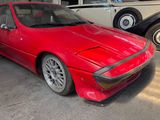 a red car parked in a garage next to a white car