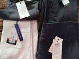 three pairs of men ' s pants with tags on them on a wooden table