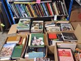 boxes of books are stacked on a table in front of a bookshelf