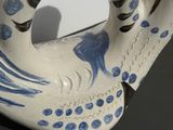 a white and blue bird shaped teapot on a black table