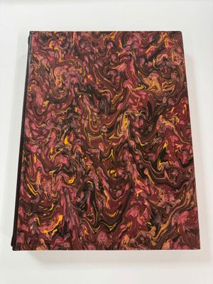 a close up of a book on a white surface with a red and yellow marble pattern