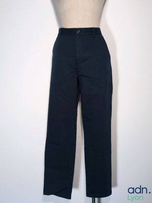 un pantalon noir sur un mannequin, posé contre un mur blanc