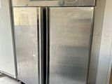 two stainless steel refrigerators in a room with concrete flooring