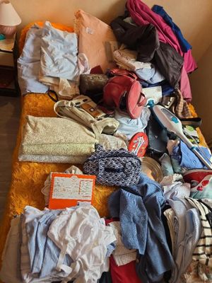 un lit sur lequel sont posés beaucoup de vêtements