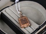 une petite médaille d'or dans un écrin posé sur une surface noire
